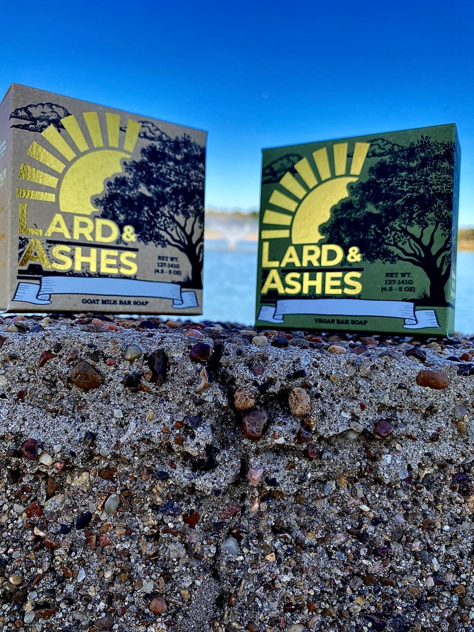 A couple of Lard and Ashes Soap boxes sitting on top of a rock